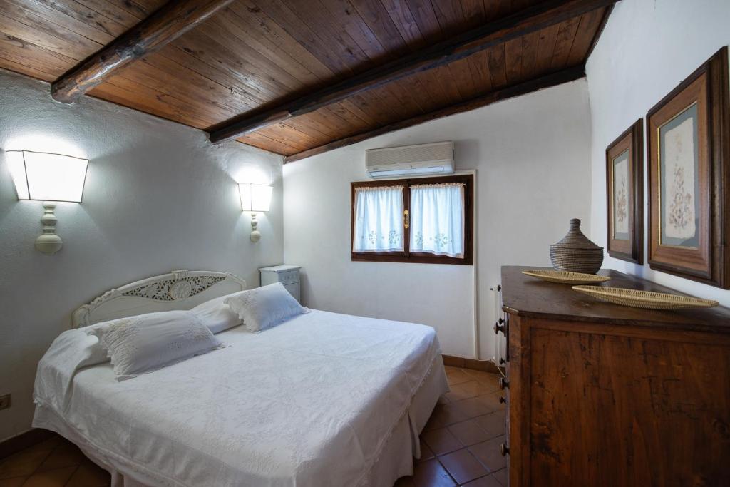 - une chambre avec un lit blanc et un plafond en bois dans l'établissement Porto Ercole Prestige Villa, à Cala Galera
