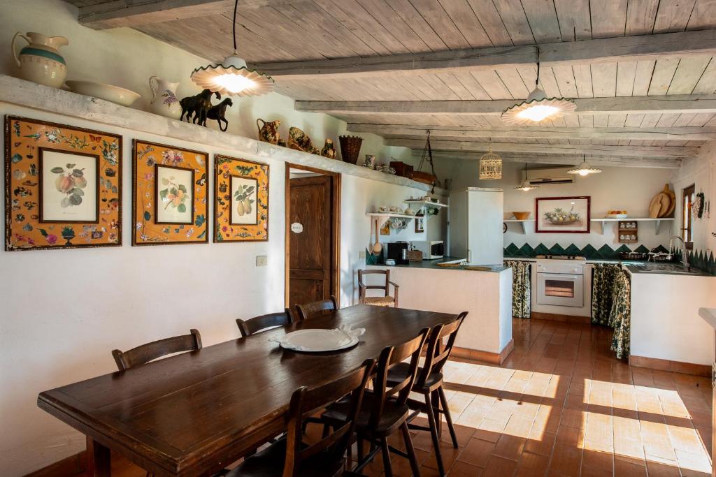 une cuisine et une salle à manger avec une table et des chaises en bois dans l'établissement Porto Ercole Prestige Villa, à Cala Galera