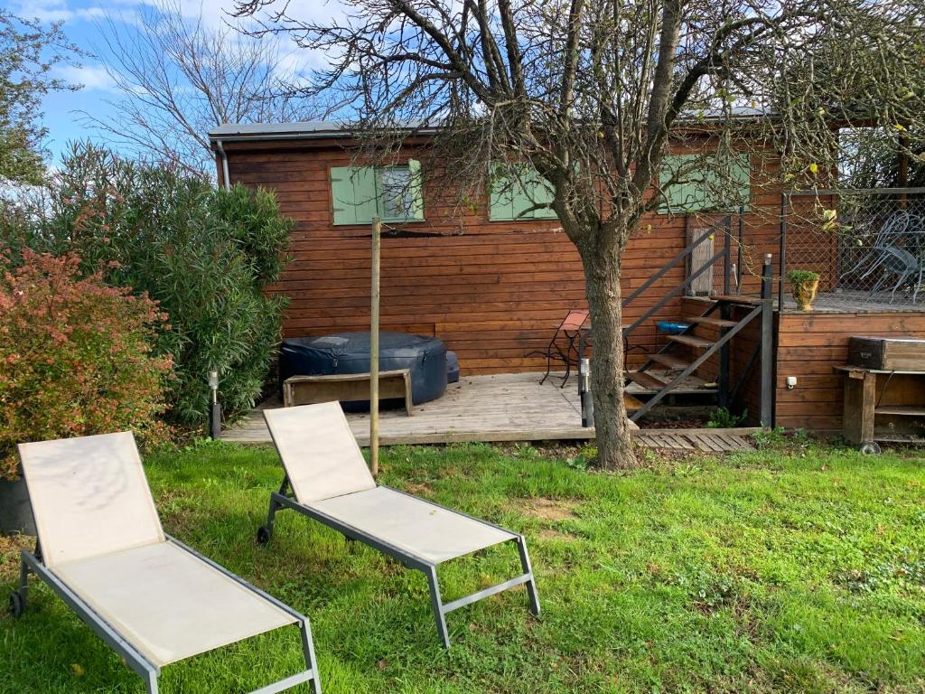 deux chaises assises dans l'herbe devant une maison dans l'établissement Roulotte et Nature, à Mirepoix