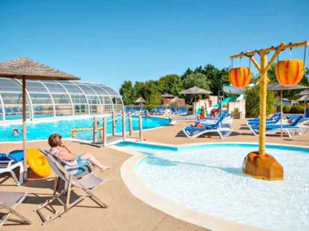 une femme assise sur une chaise à côté d'une piscine dans l'établissement Camping 4 étoiles - Parc aquatique - eeiaei, à Givrand 21 autres photos