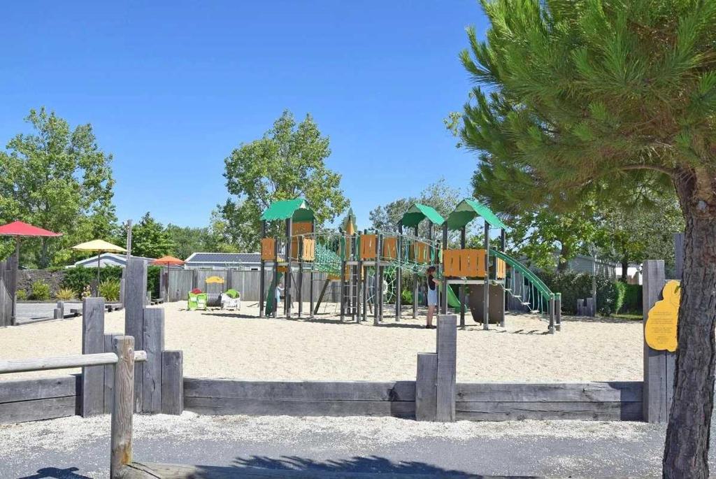 - une aire de jeux dans un parc avec un arbre dans l'établissement Camping 4 étoiles - Parc aquatique - eeiaei, à Givrand