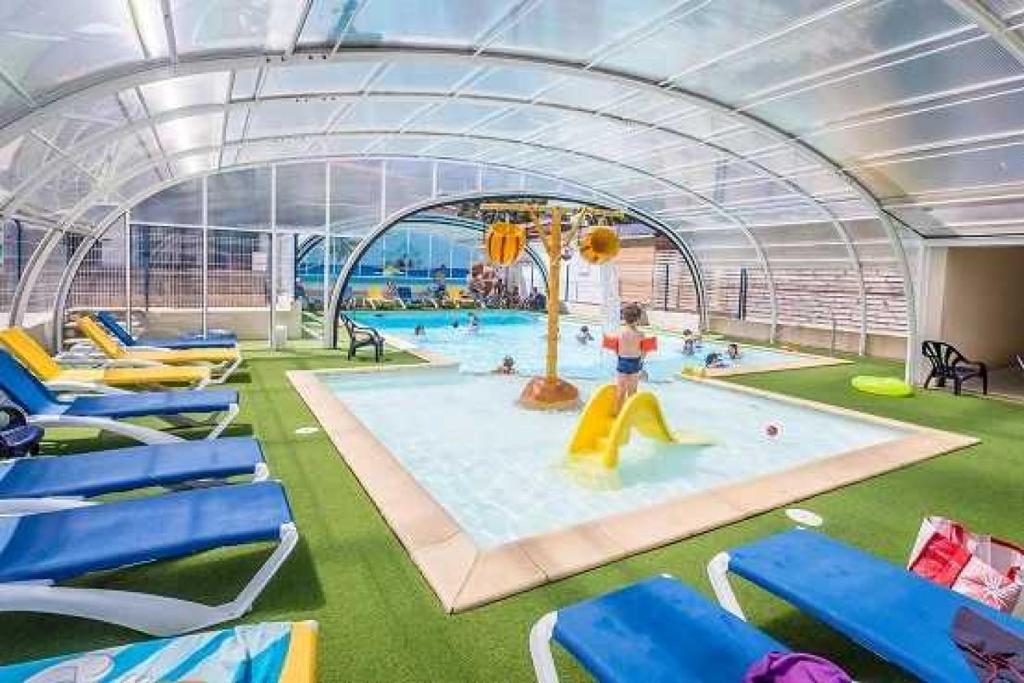 - une grande piscine avec des chaises bleues dans l'établissement Camping 4 étoiles - Piscine - eei0fg, à La Faute-sur-Mer