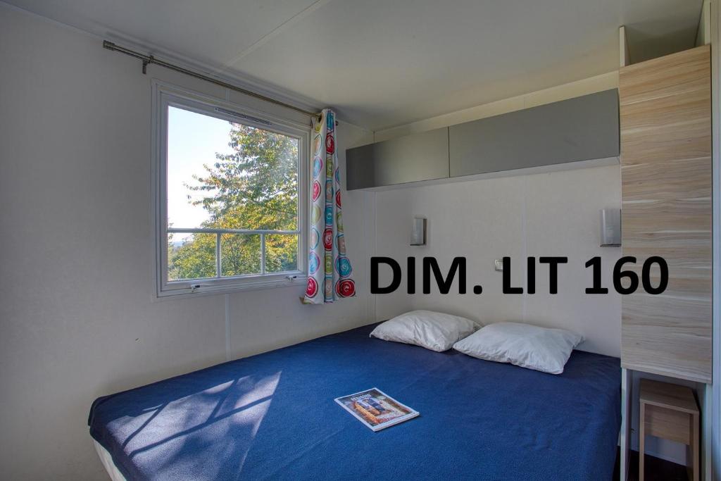 une chambre avec un lit bleu avec une fenêtre dans l'établissement Camping Brin d'Amour, à Les Eyzies-de-Tayac