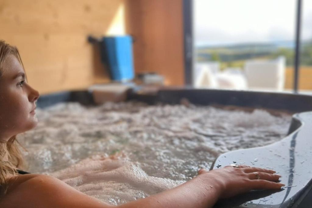 une jeune fille est dans une baignoire dans l'établissement La Flèche 1 - Chalet Standing - Jacuzzi Privatif, à Besse-et-Saint-Anastaise