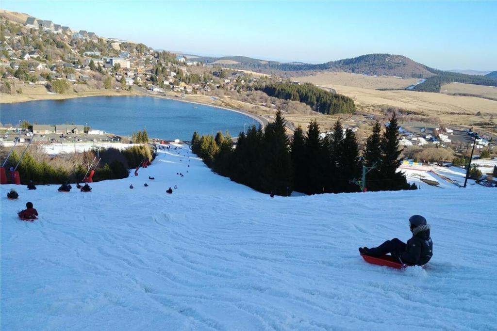 une personne assise dans la neige sur un snowboard dans l'établissement La Flèche 1 - Chalet Standing - Jacuzzi Privatif, à Besse-et-Saint-Anastaise 37 autres photos