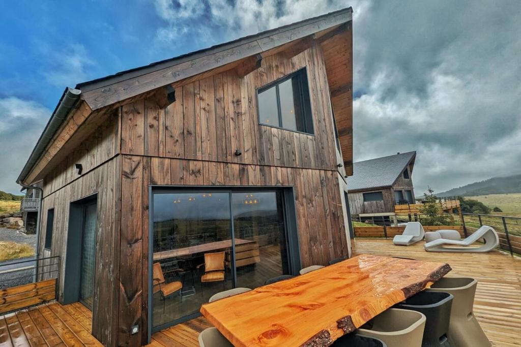 Ce chalet en bois dispose d'une table et d'une grande fenêtre. dans l'établissement La Flèche 2 - Chalet Standing - Jacuzzi Privatif, à Besse-et-Saint-Anastaise
