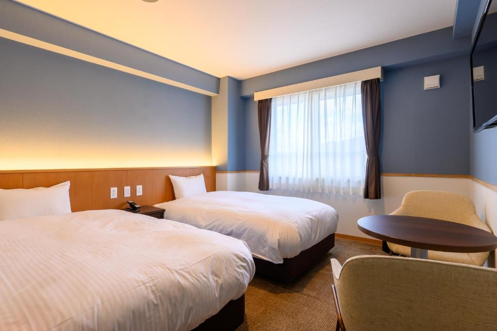 une chambre d'hôtel avec deux lits et une fenêtre dans l'établissement Kojohama Onsen Hotel, à Shiraoi 37 autres photos