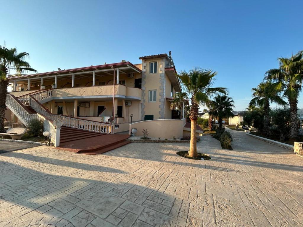 une grande maison avec des palmiers devant dans l'établissement Residence Parco del Sole, à Rodi Garganico