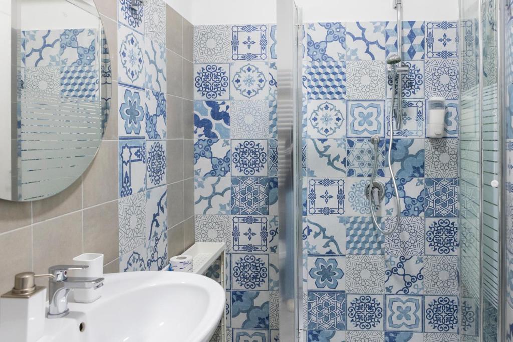 La salle de bains bleue et blanche est pourvue d'un lavabo et d'une douche. dans l'établissement Sperlonga Center Holiday B&B, à Sperlonga