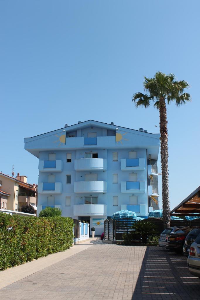un bâtiment avec un palmier à côté d'un parking dans l'établissement Residence Blumarine, à Giulianova