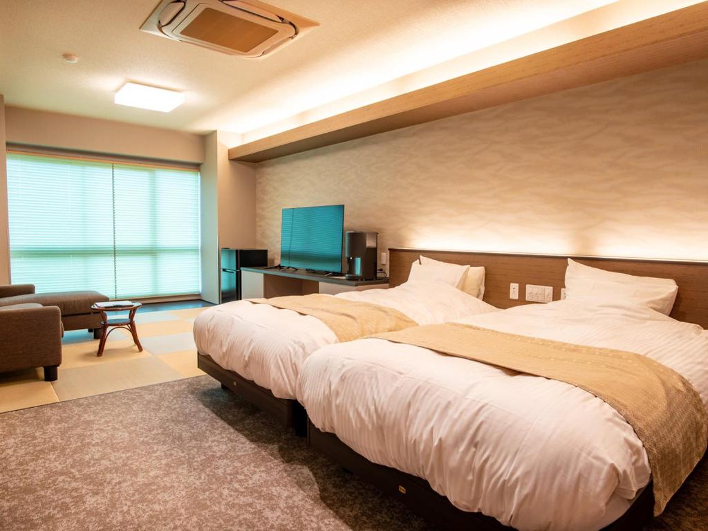 une chambre avec deux lits et une télévision à écran plat dans l'établissement Ise-Shima Ohtaya Healing Stay, à Toba