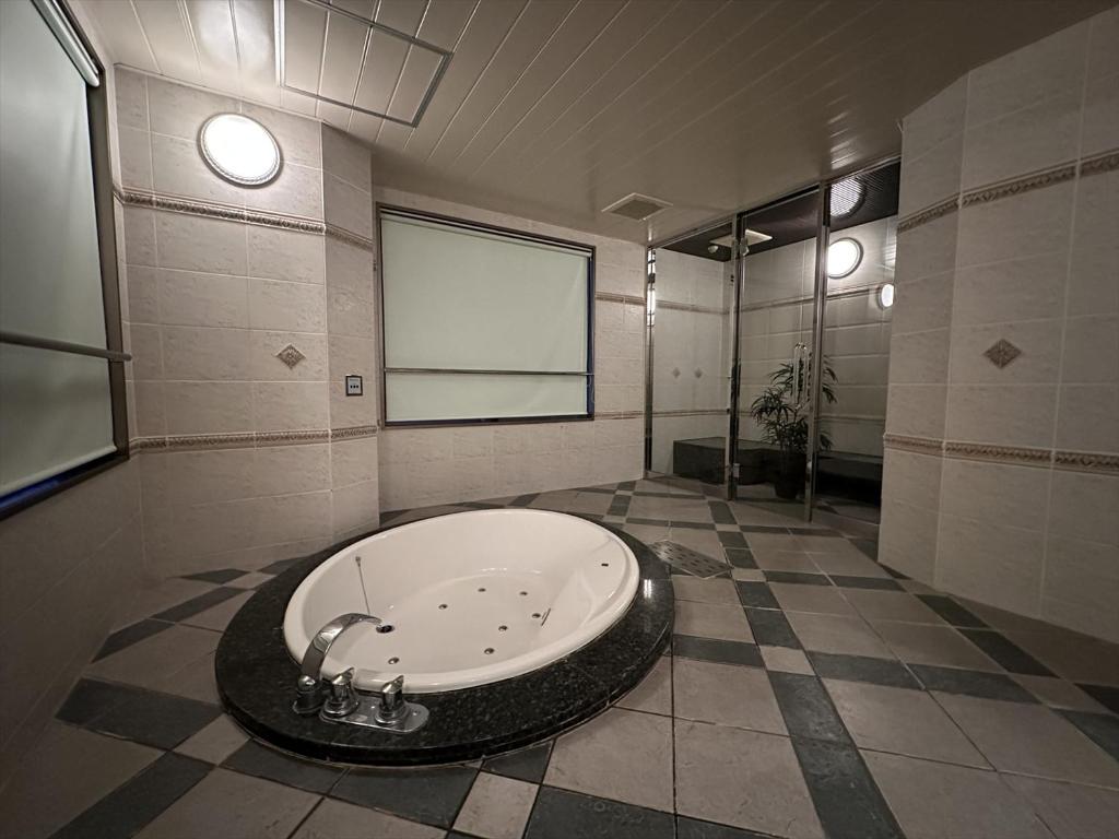 Cette chambre comprend une salle de bains pourvue d'une grande baignoire. dans l'établissement ホテルk2, à Itoshima