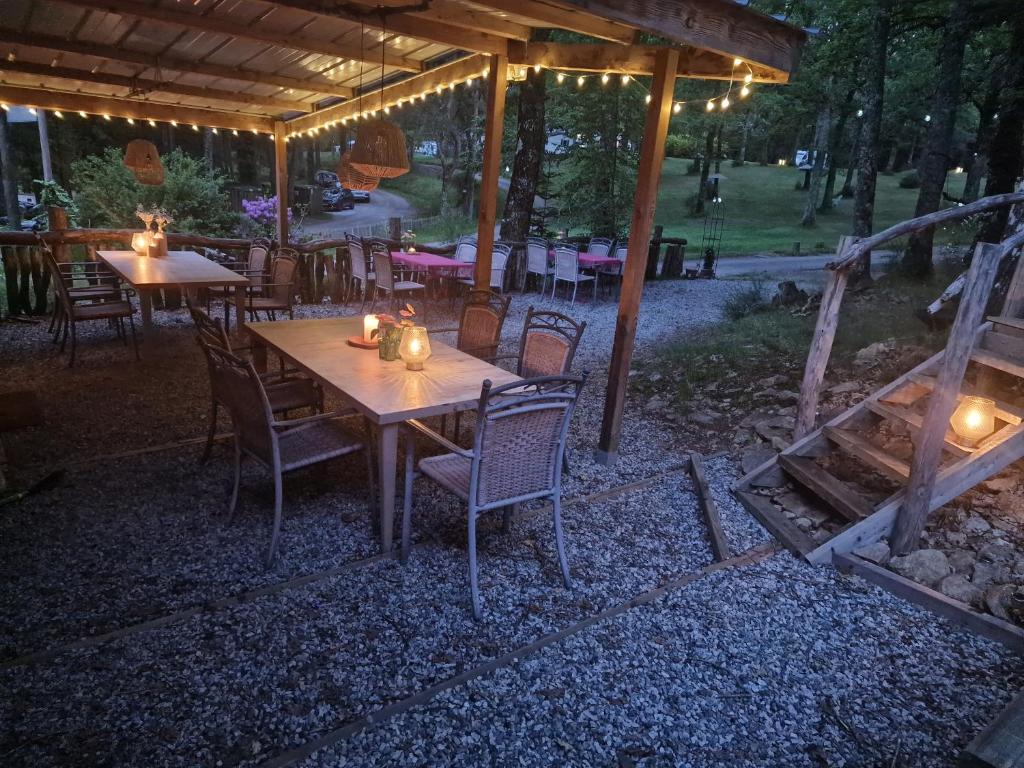 une table et des chaises en bois sous un pavillon avec des lumières dans l'établissement Camping Montard, à Lamongerie
