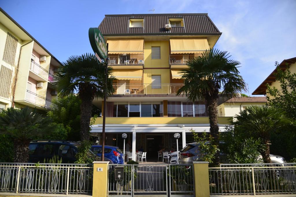 un bâtiment jaune avec des palmiers devant dans l'établissement HOTEL LA PLAYA, à Cervia