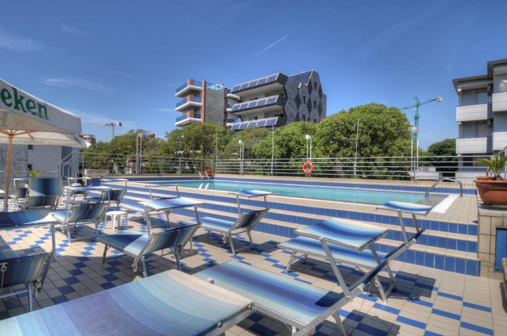 une piscine avec chaises et tables à côté d'un bâtiment dans l'établissement Hotel Blue Marine, à Lignano Sabbiadoro