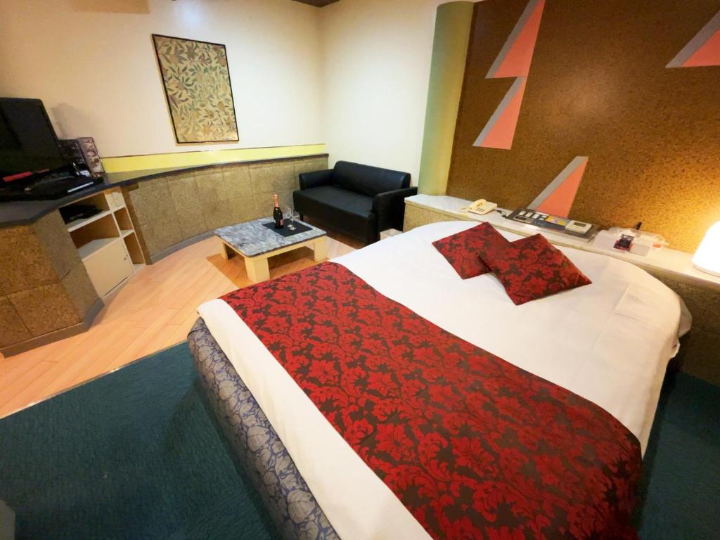 une chambre d'hôtel avec un grand lit et une chaise dans l'établissement HOTEL K's GOMANGOKU adult only, à Takatsuka