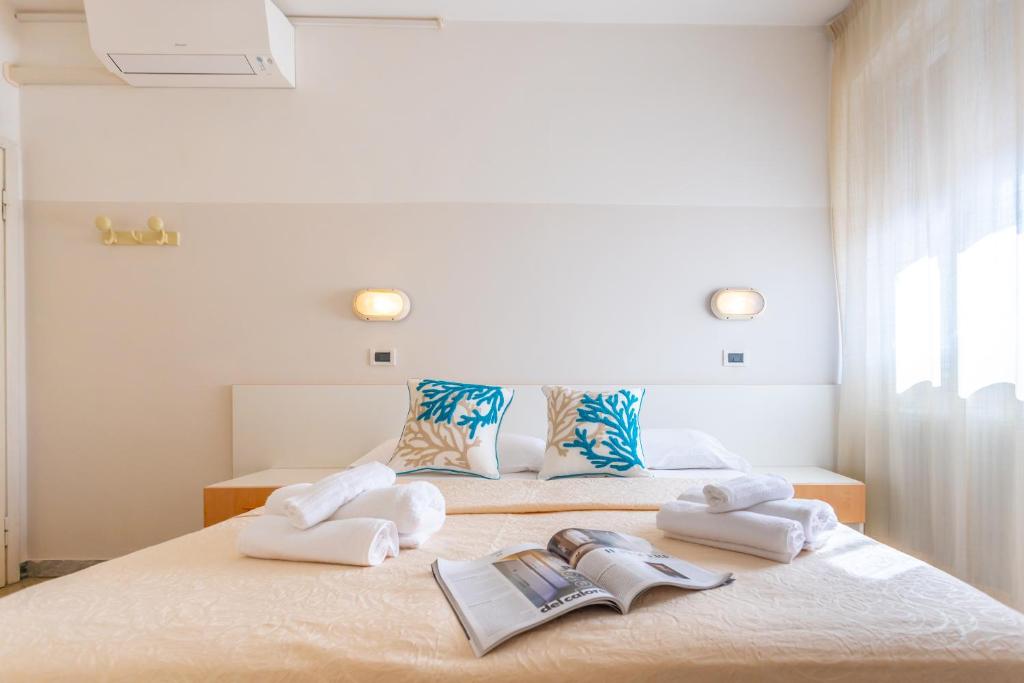 une chambre avec deux lits, des serviettes et des livres dans l'établissement Hotel Selene - Vista Mare, à Riccione