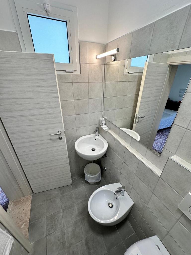 une salle de bain avec un lavabo, des toilettes et un miroir dans l'établissement Hotel Napoleon, à Riccione