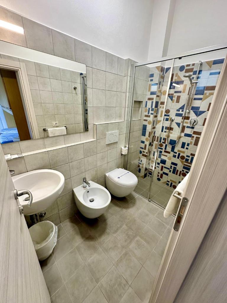 La salle de bains est pourvue de 2 toilettes, d'un lavabo et d'un miroir. dans l'établissement Hotel Napoleon, à Riccione 55 autres photos