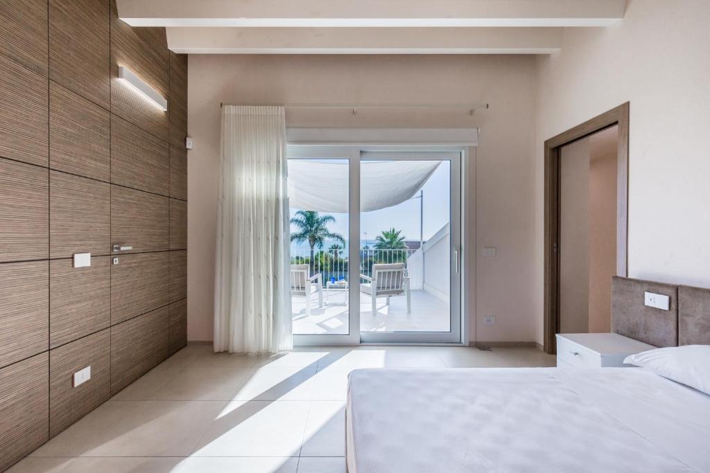 une chambre avec un lit et une vue sur l'océan dans l'établissement Dione Villa Mare di Ponente, à Donnalucata