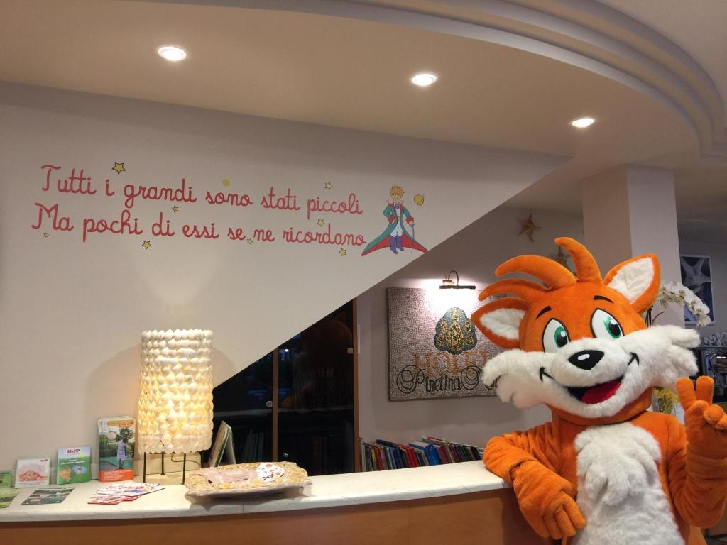 Une mascotte se tient devant un comptoir dans l'établissement Pinetina Mare Baby Family Hotel, à Cervia