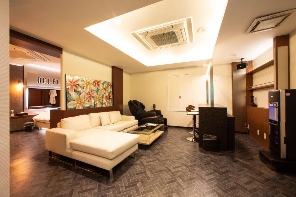 un salon avec un canapé et une télévision dans l'établissement ホテルベルファス, à Koriyama