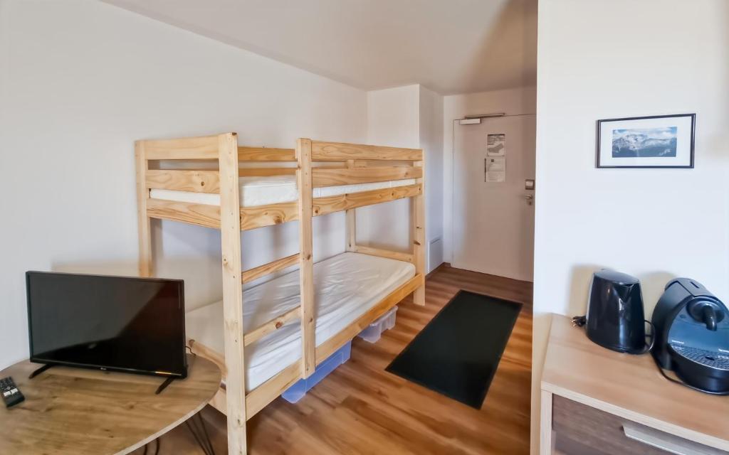 Cette chambre dispose de lits superposés et d'un bureau avec une télévision. dans l'établissement Studio Le Panoramic les Balcons d'Aix, à La Féclaz