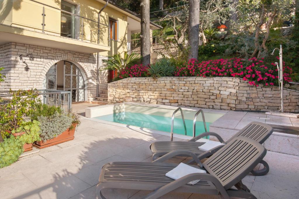 - deux chaises assises à côté de la piscine dans l'établissement Villa Vista Lago With Pool, à Torri del Benaco