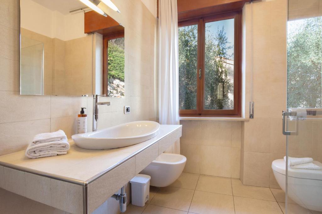 une salle de bain avec un lavabo et des toilettes dans l'établissement Villa Vista Lago With Pool, à Torri del Benaco