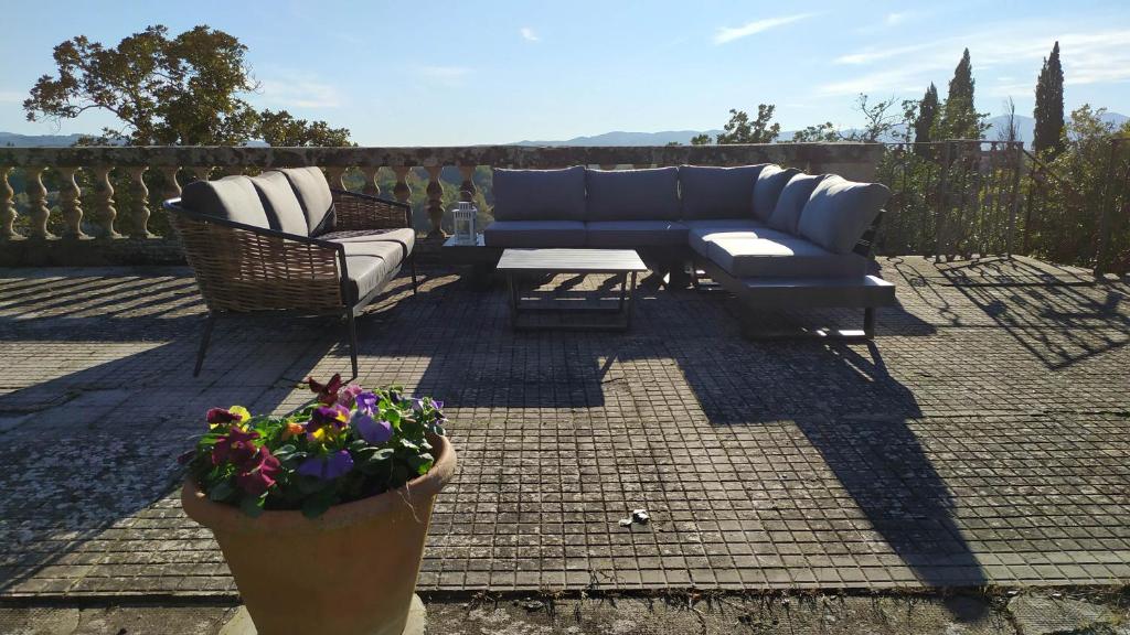une terrasse avec un canapé bleu, des chaises et des fleurs dans l'établissement Total Tuscany Countryside Villa, à Terranuova Bracciolini 51 autres photos