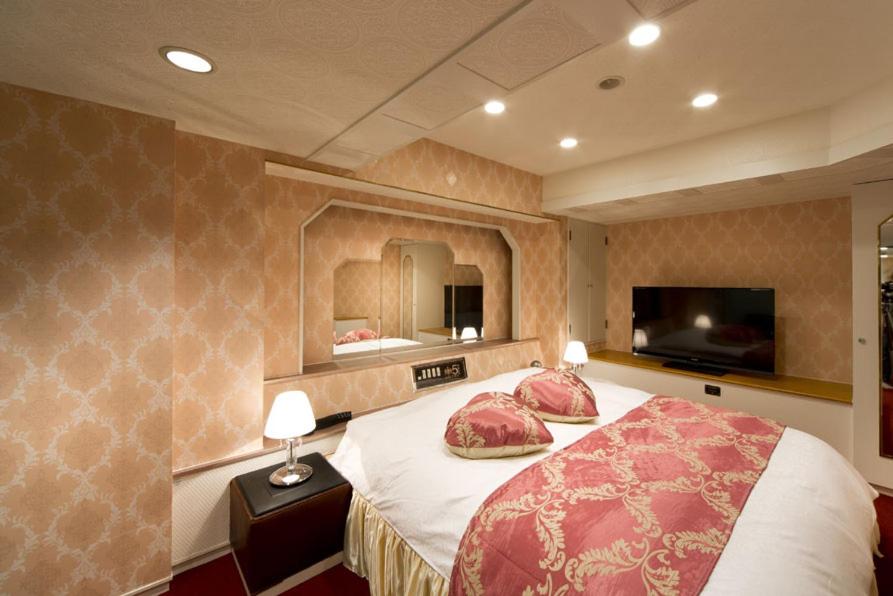 une chambre avec un lit avec deux oreillers et un miroir dans l'établissement HOTEL FIVE -Adult Only-, à Osaka