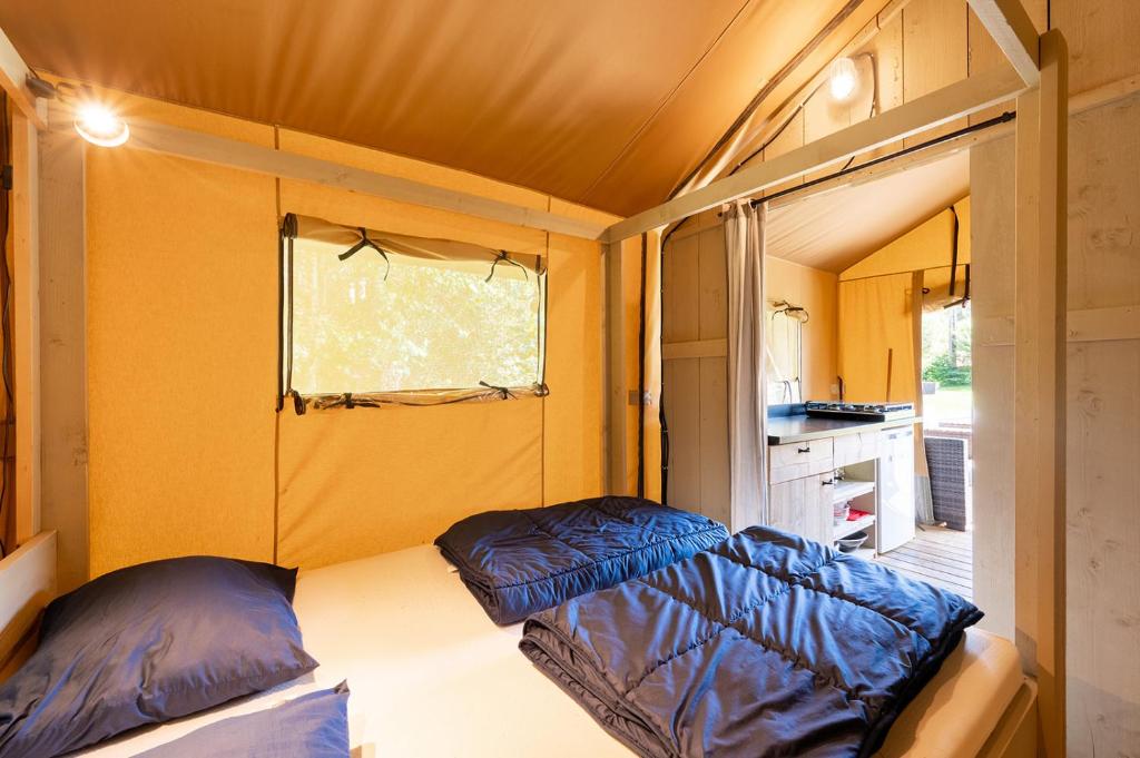 une petite pièce avec un lit et une fenêtre dans l'établissement Glamping Haure-Loire, à Sainte-Sigolène