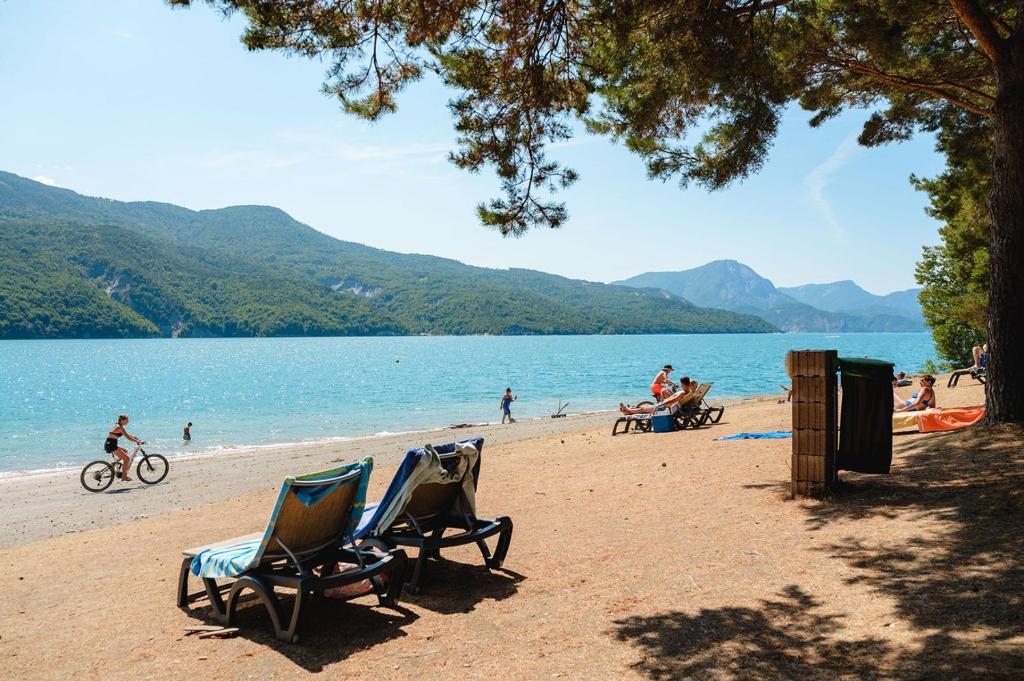 - une plage avec des chaises et des personnes sur l'eau dans l'établissement Glamping Hautes-Alpes, à Prunières