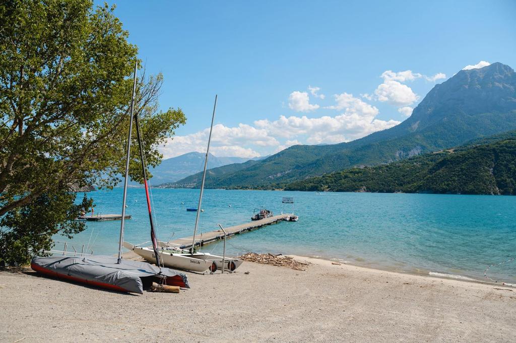 un groupe de bateaux assis sur la rive d'un lac dans l'établissement Glamping Hautes-Alpes, à Prunières