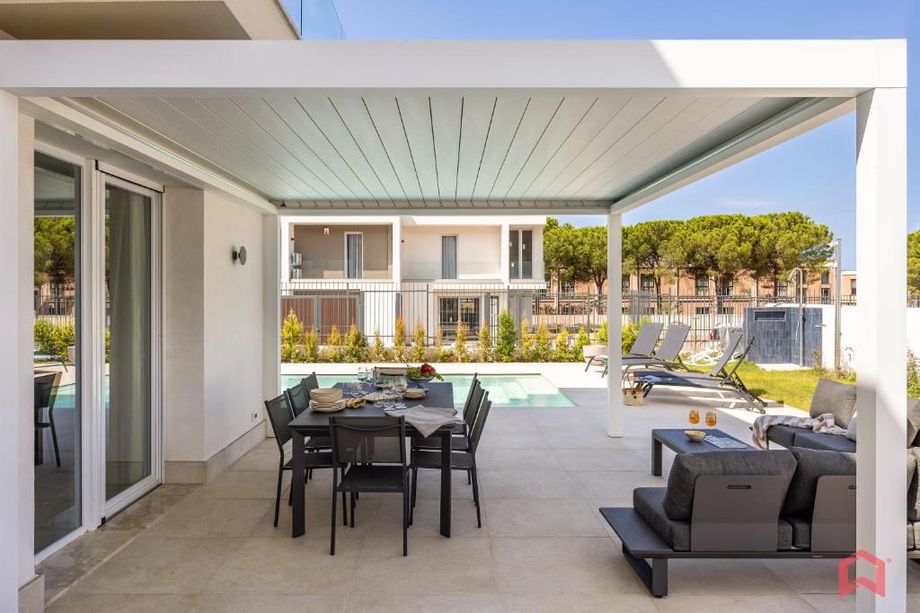 une terrasse ouverte avec une table, des chaises et une piscine dans l'établissement Brand New Villa with Private Heated Pool, à Terrasini