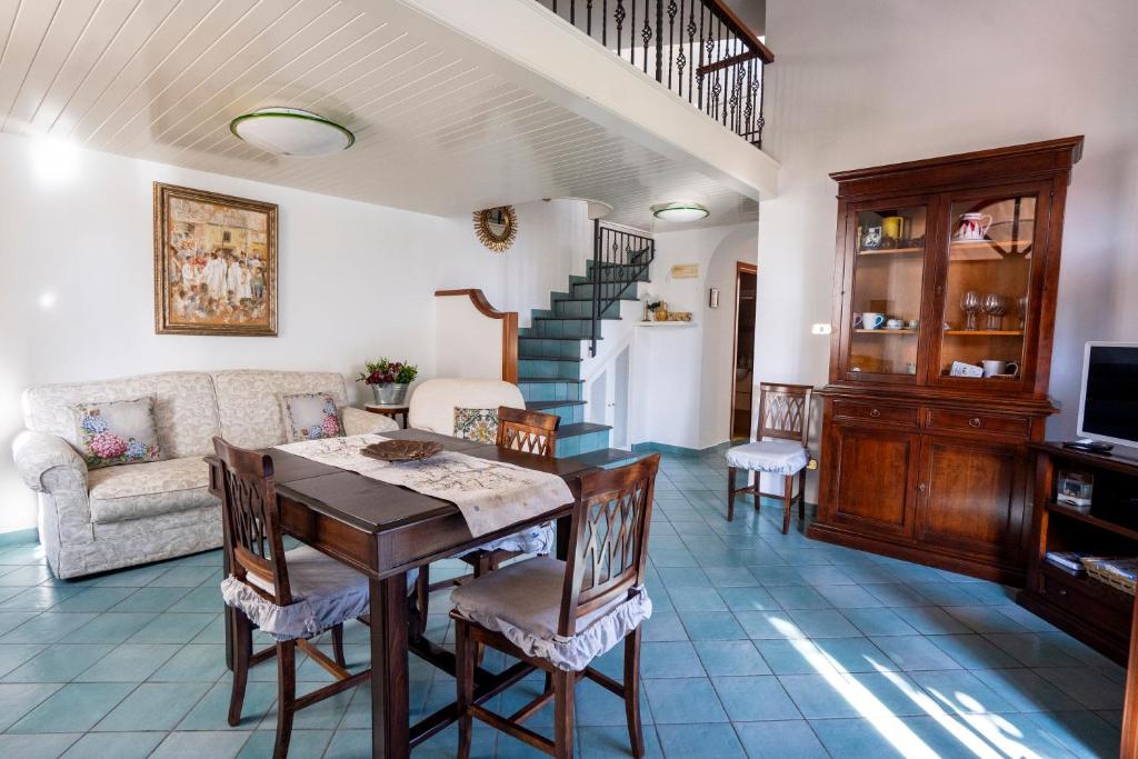 un salon avec une table et des chaises et un escalier dans l'établissement Villa Miramare, piscina e parcheggio a Conca dei Marini, à Conca dei Marini