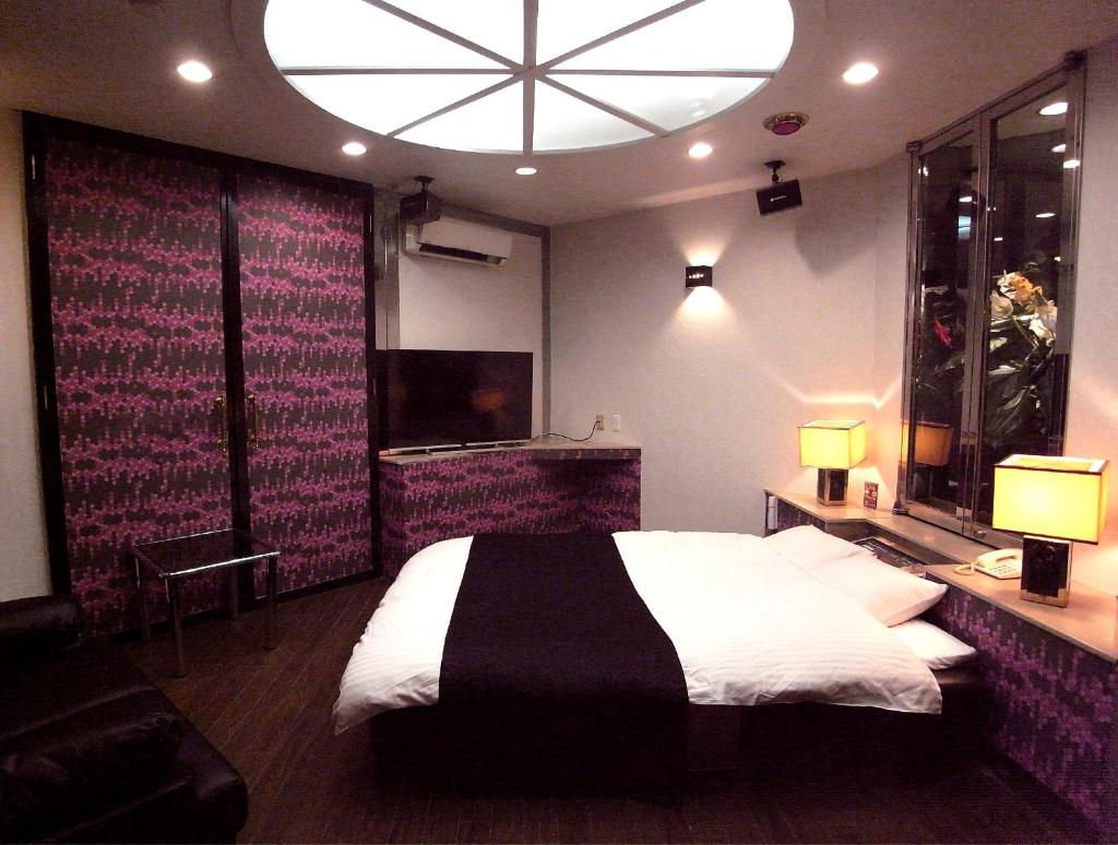 une chambre avec un grand lit et une grande fenêtre dans l'établissement ホテル暴れ狸の鬼袋姫路駅前店 男塾ホテルグループ, à Himeji