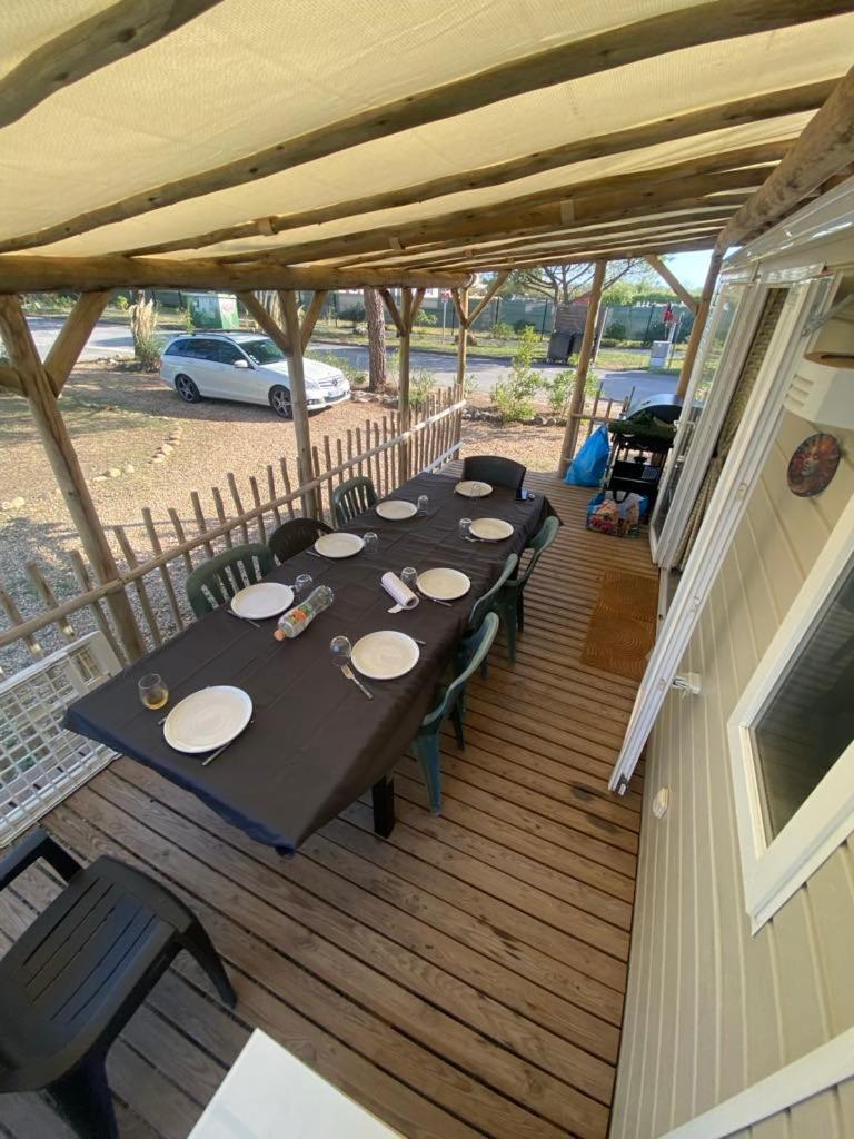 une terrasse en bois avec une grande table et des chaises dans l'établissement Lac Des Reves Monparadis 58, à Lattes