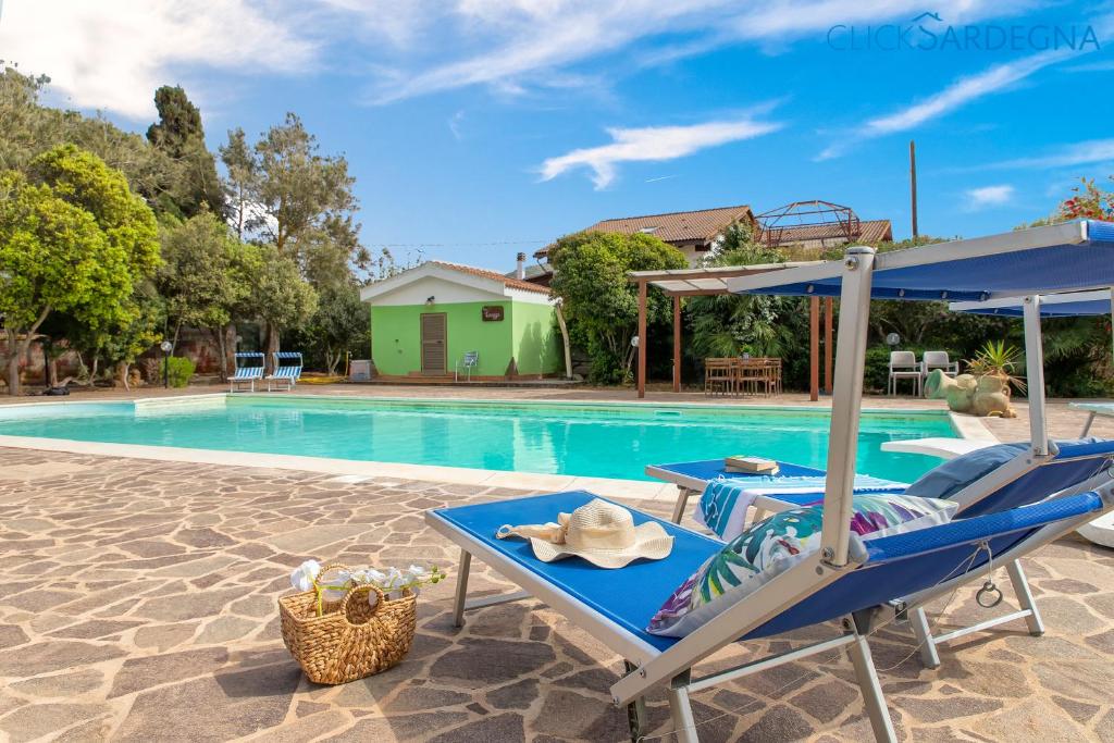 - une piscine avec une chaise longue bleue et une table dans l'établissement Villa Melograno with exclusive swimming pool surrounded by greenery, à Campanedda