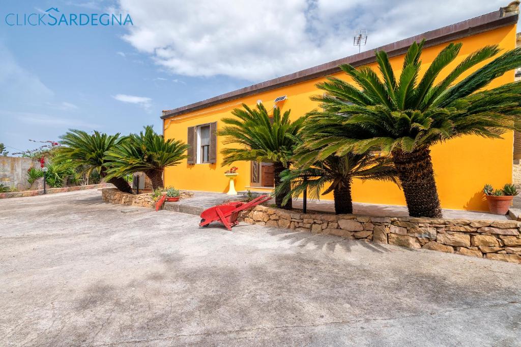 un bâtiment jaune avec des palmiers devant lui dans l'établissement Villa Melograno with exclusive swimming pool surrounded by greenery, à Campanedda