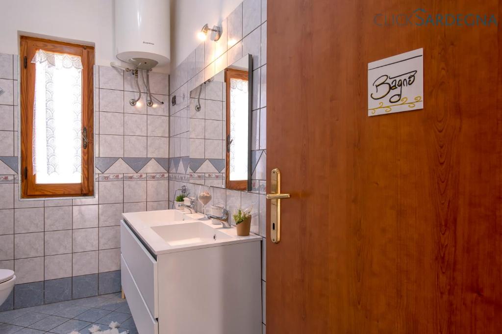 La salle de bains est pourvue d'un lavabo et d'une porte en bois. dans l'établissement Villa Melograno with exclusive swimming pool surrounded by greenery, à Campanedda