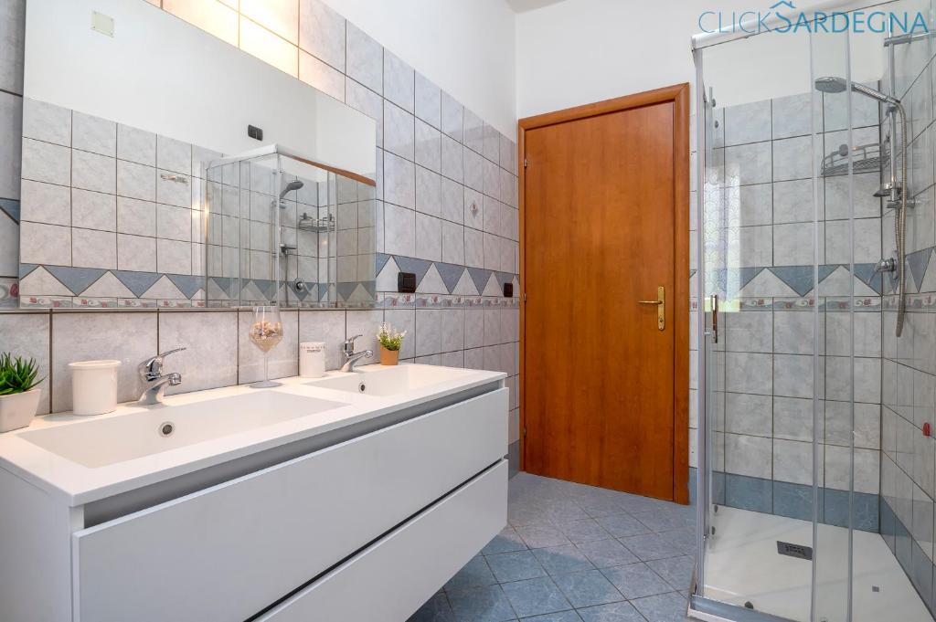 une salle de bain avec deux lavabos et une douche dans l'établissement Villa Melograno with exclusive swimming pool surrounded by greenery, à Campanedda 34 autres photos