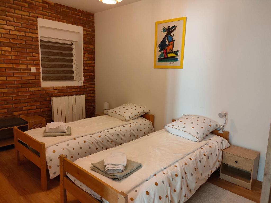 - 2 lits jumeaux dans une chambre avec un mur en briques dans l'établissement bel appartement 3 pièces dans la Résidence Vosges-Alsace Orbey, à Orbey