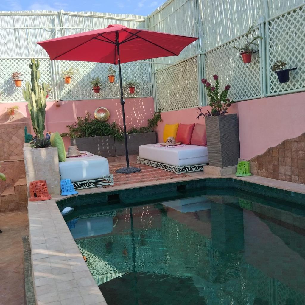 une terrasse avec une piscine, un parasol et un canapé dans l'établissement Riad Laith, à Marrakech