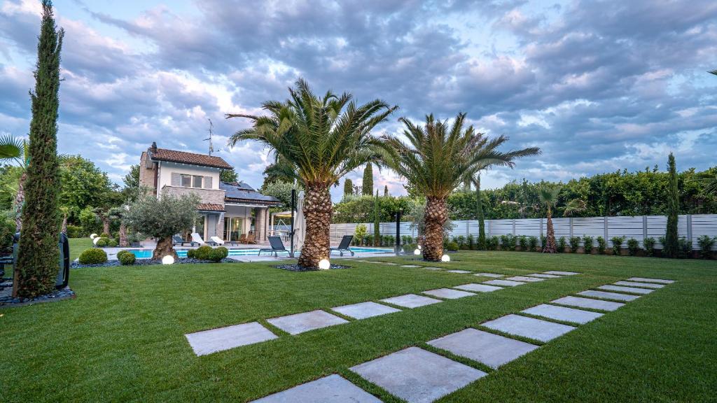 une cour avec des palmiers et une maison dans l'établissement Villa Sirmione Front Lake, à Sirmione