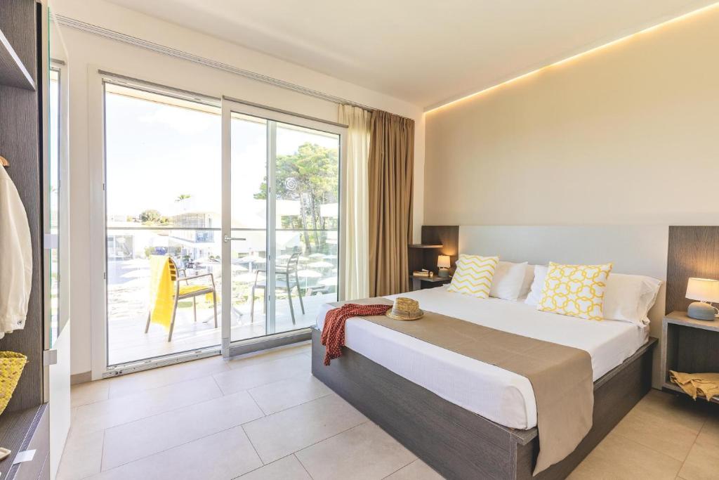 une chambre avec un grand lit et une grande fenêtre dans l'établissement TUISuneo La Conchiglia - Adults Only, à Capo Vaticano