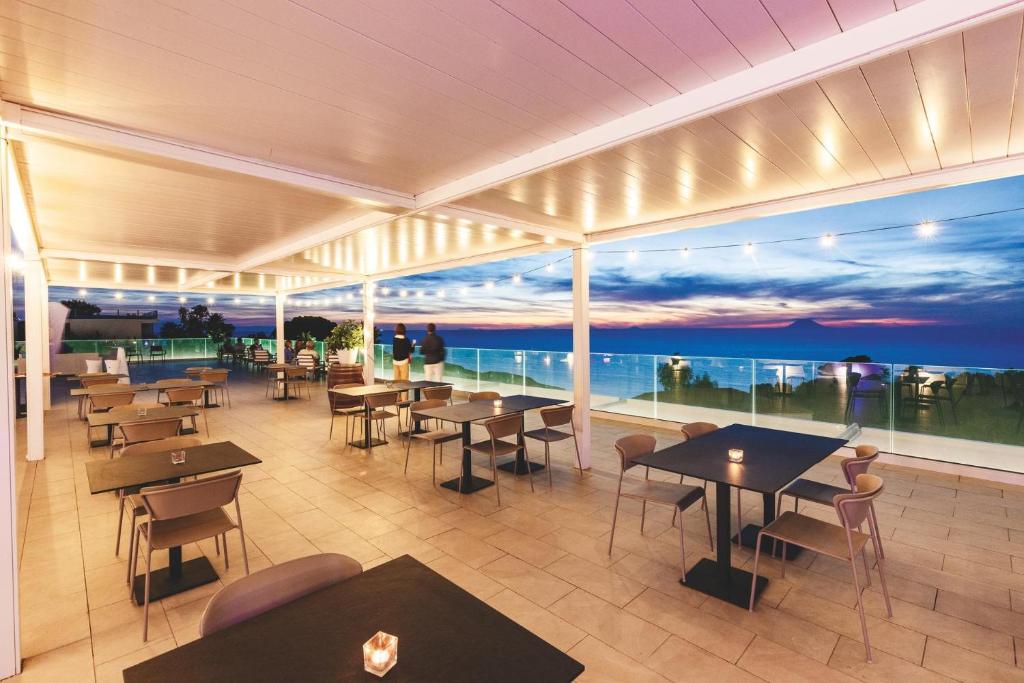 un restaurant avec des tables et des chaises et une vue sur l'océan dans l'établissement TUISuneo La Conchiglia - Adults Only, à Capo Vaticano