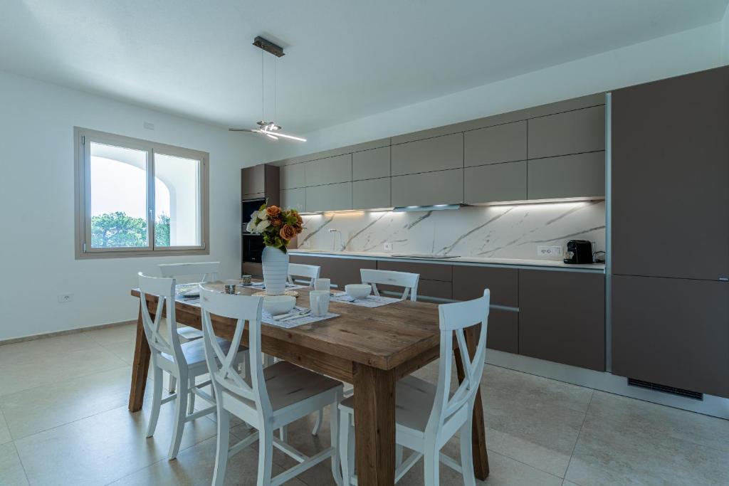 - une cuisine avec une table en bois et des chaises blanches dans l'établissement Villa Infinity with Pool by Wonderful Italy, à Olbia