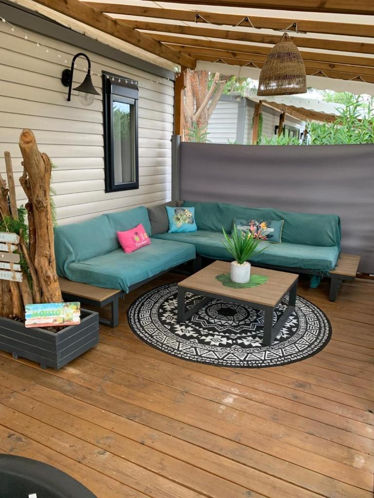 une terrasse avec un canapé bleu et une table dans l'établissement Camping Del Mar B06, Mobile Home Excellence, 3 chambres, 6 places, bord de mer, à Argelès-sur-Mer