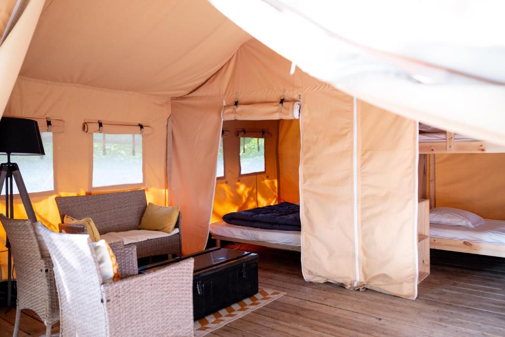 Cette chambre comprend une tente avec un canapé et un lit. dans l'établissement Camping De Thoissey ***, à Thoissey